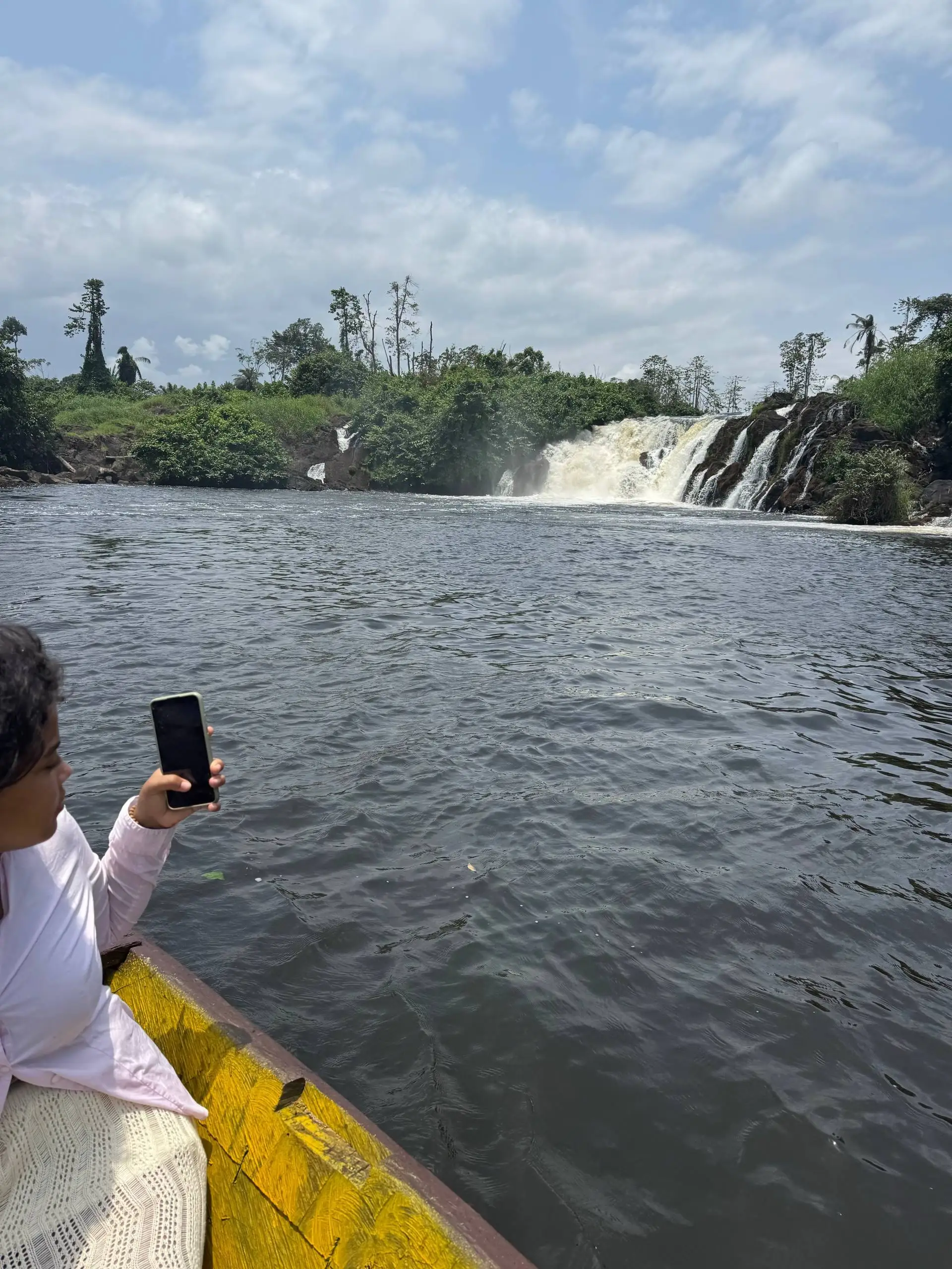 Une visiteuse photographie les chutes depuis la pirogue