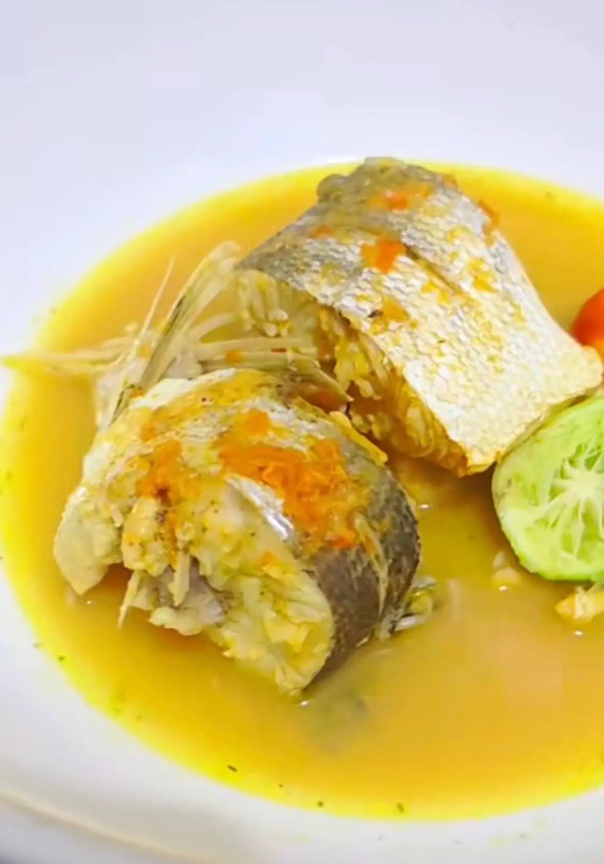 L’Ebanjea servi à l’assiette : tronçons de poisson dans un bouillon jaune relevé, citron vert