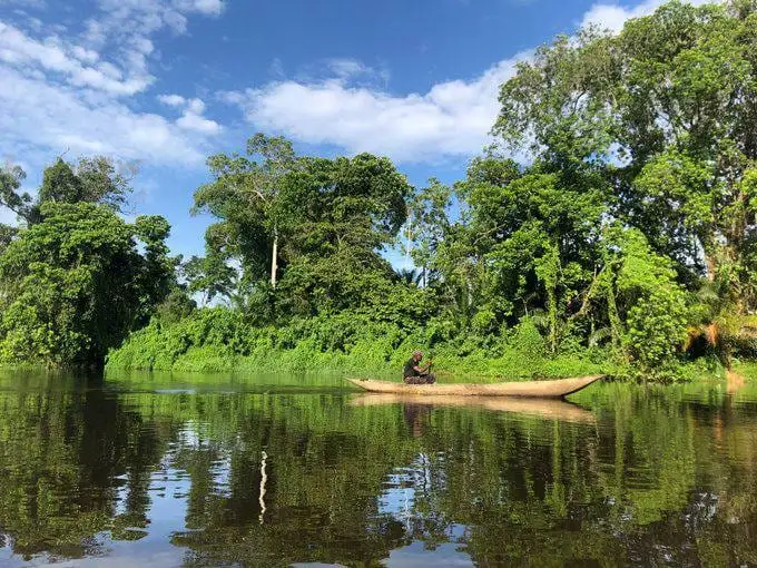 Un piroguier sur la Lobé, entre forêt et reflets