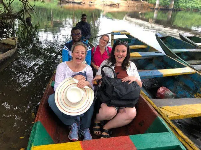 Des visiteuses souriantes assises dans une pirogue