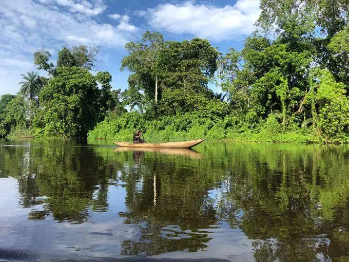 Une pirogue glisse sur la Lobé, entre forêt et reflets