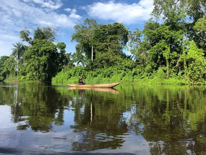 Une pirogue glisse sur la Lobé, entre forêt et reflets