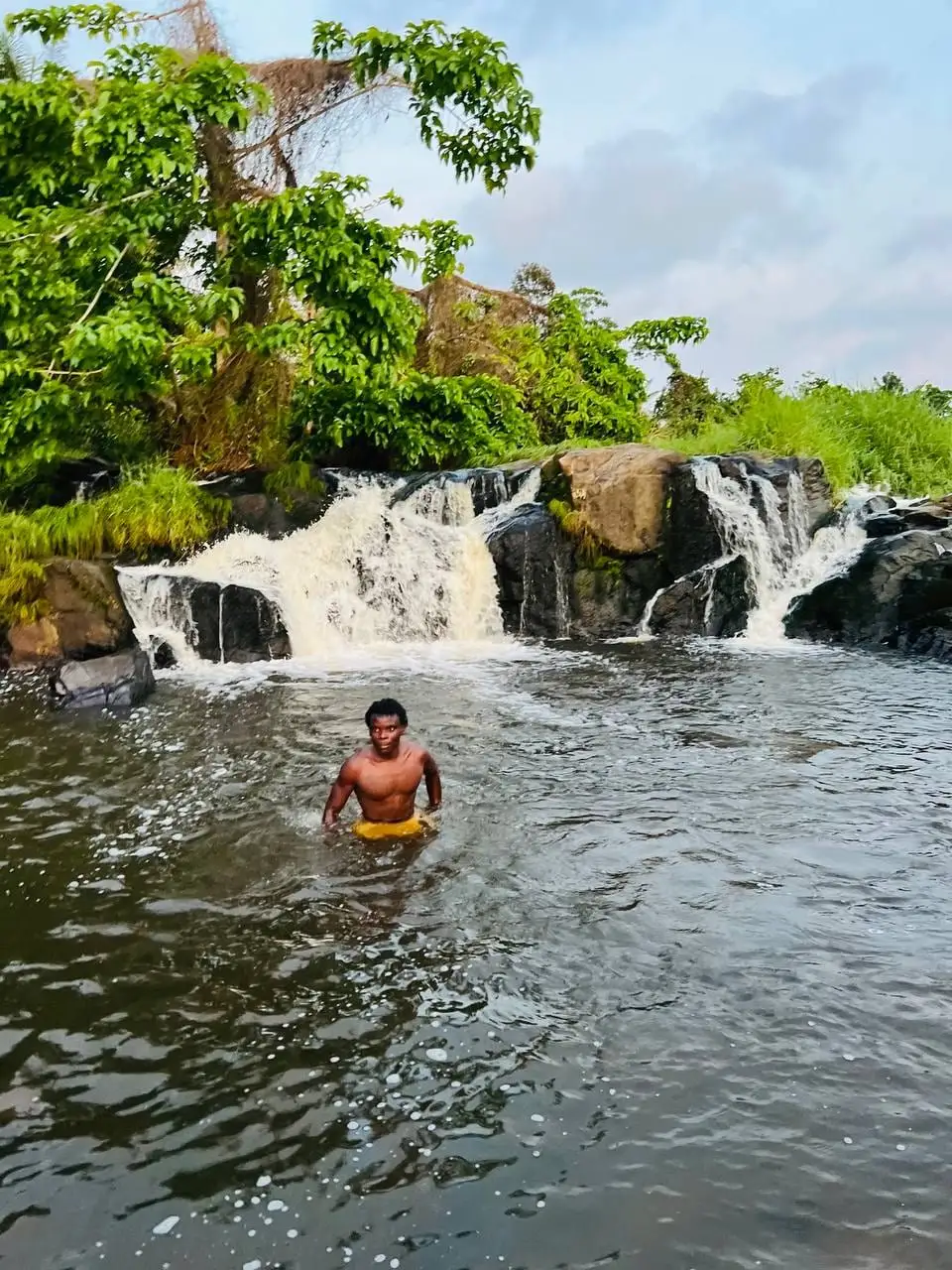 Un baigneur dans le bassin du jacuzzi naturel, devant la cascade