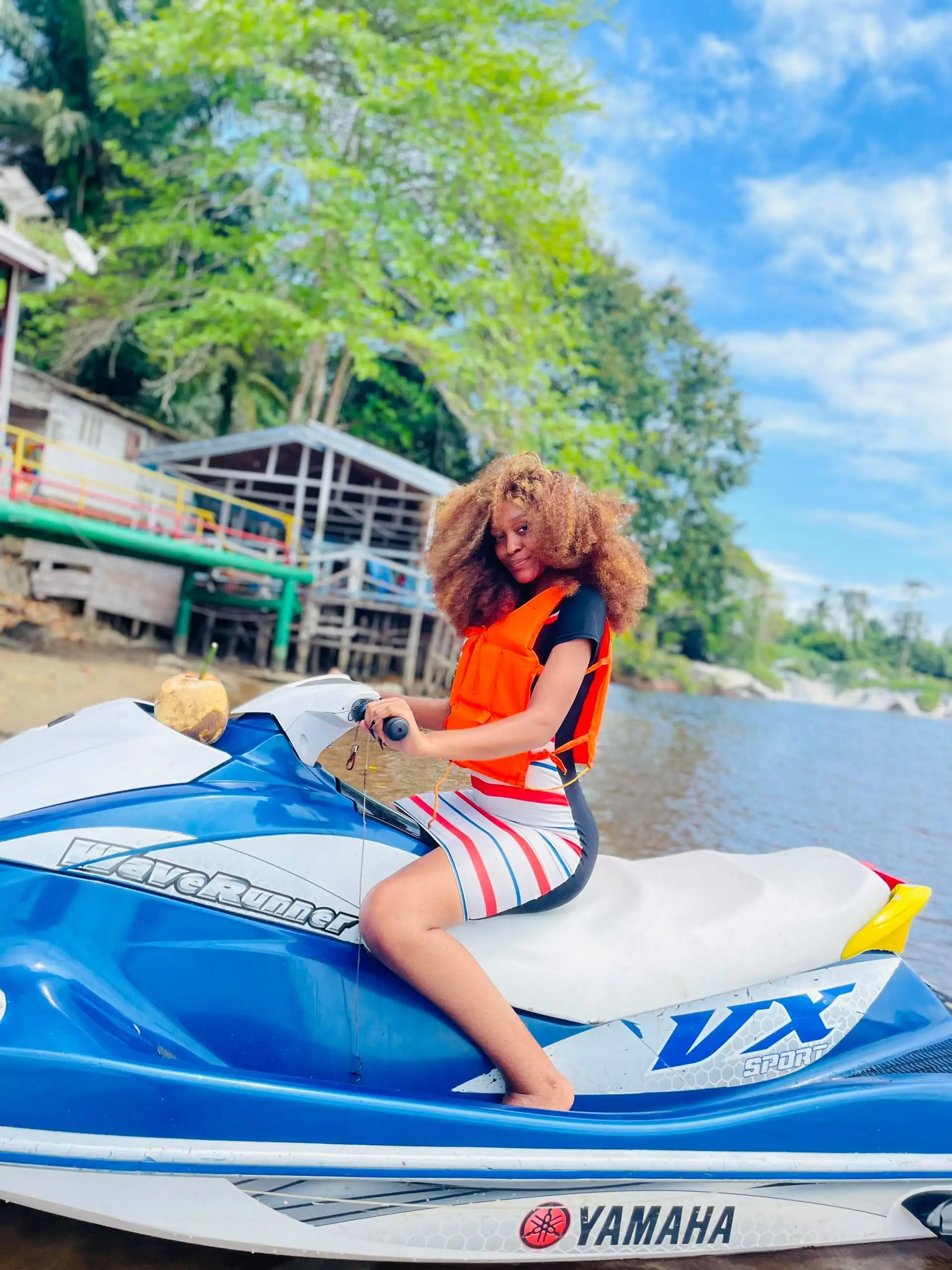 Une jeune femme pose sur un jet-ski, au bord de la rivière