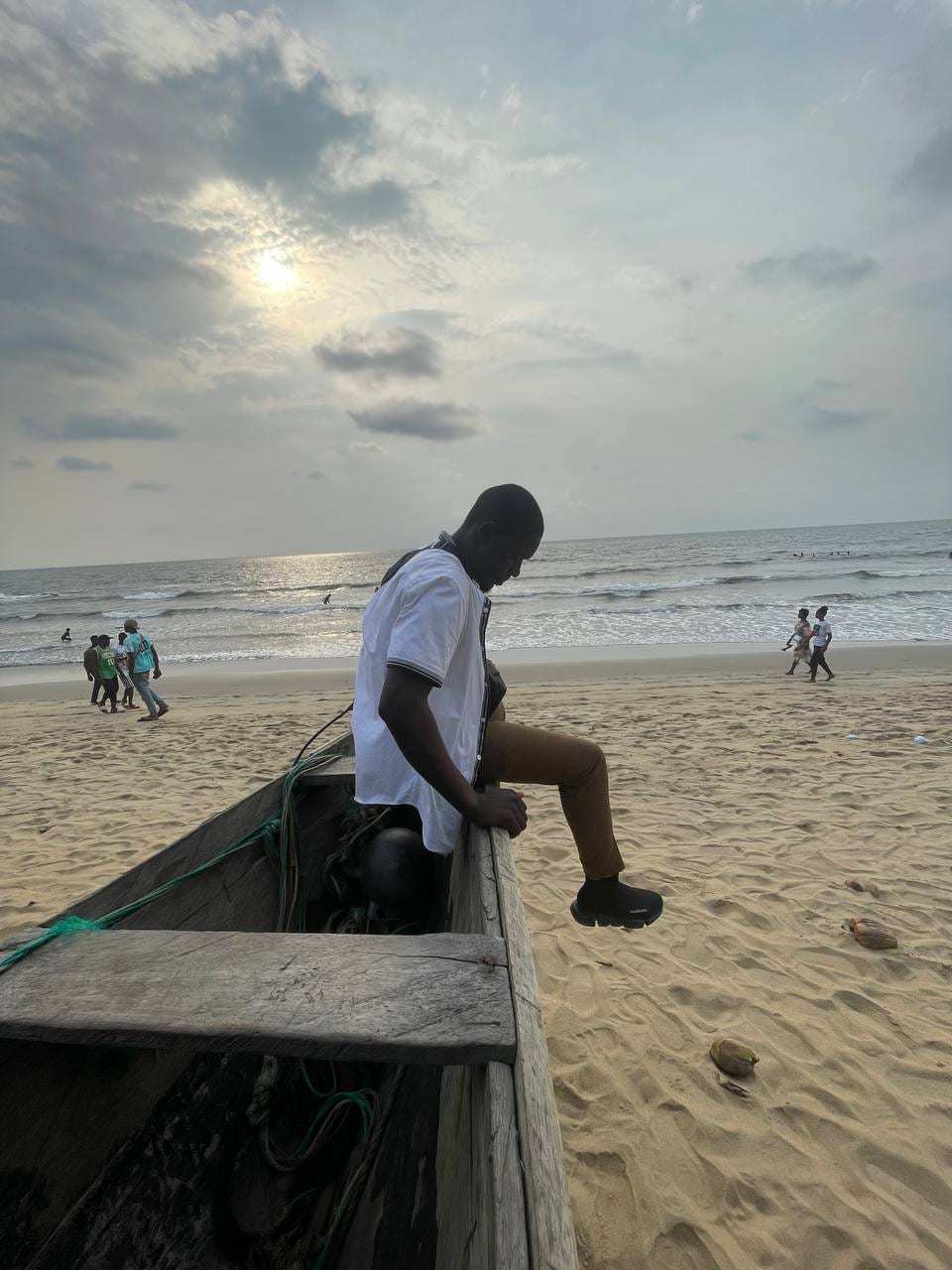 Un guide assis sur une pirogue tirée sur la plage, face à la mer