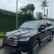 Un Toyota Land Cruiser noir garé devant une haie