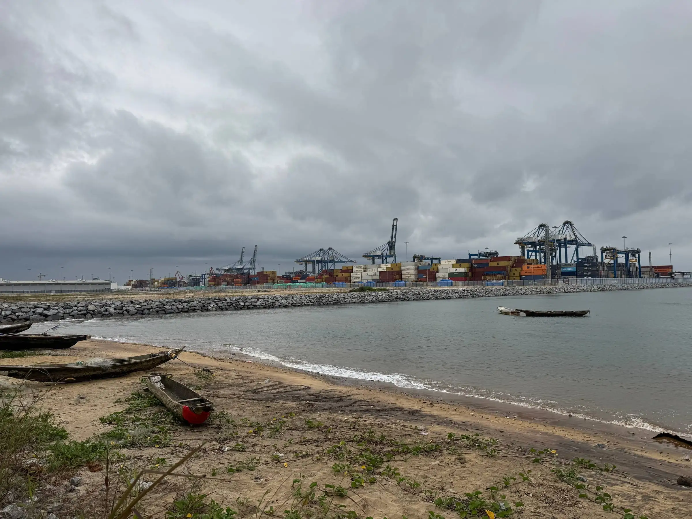 Pirogues de pêcheurs sur la plage, face aux portiques et aux conteneurs du port de Kribi