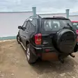 Un Toyota RAV4 noir vu de l'arrière, roue de secours sur le hayon