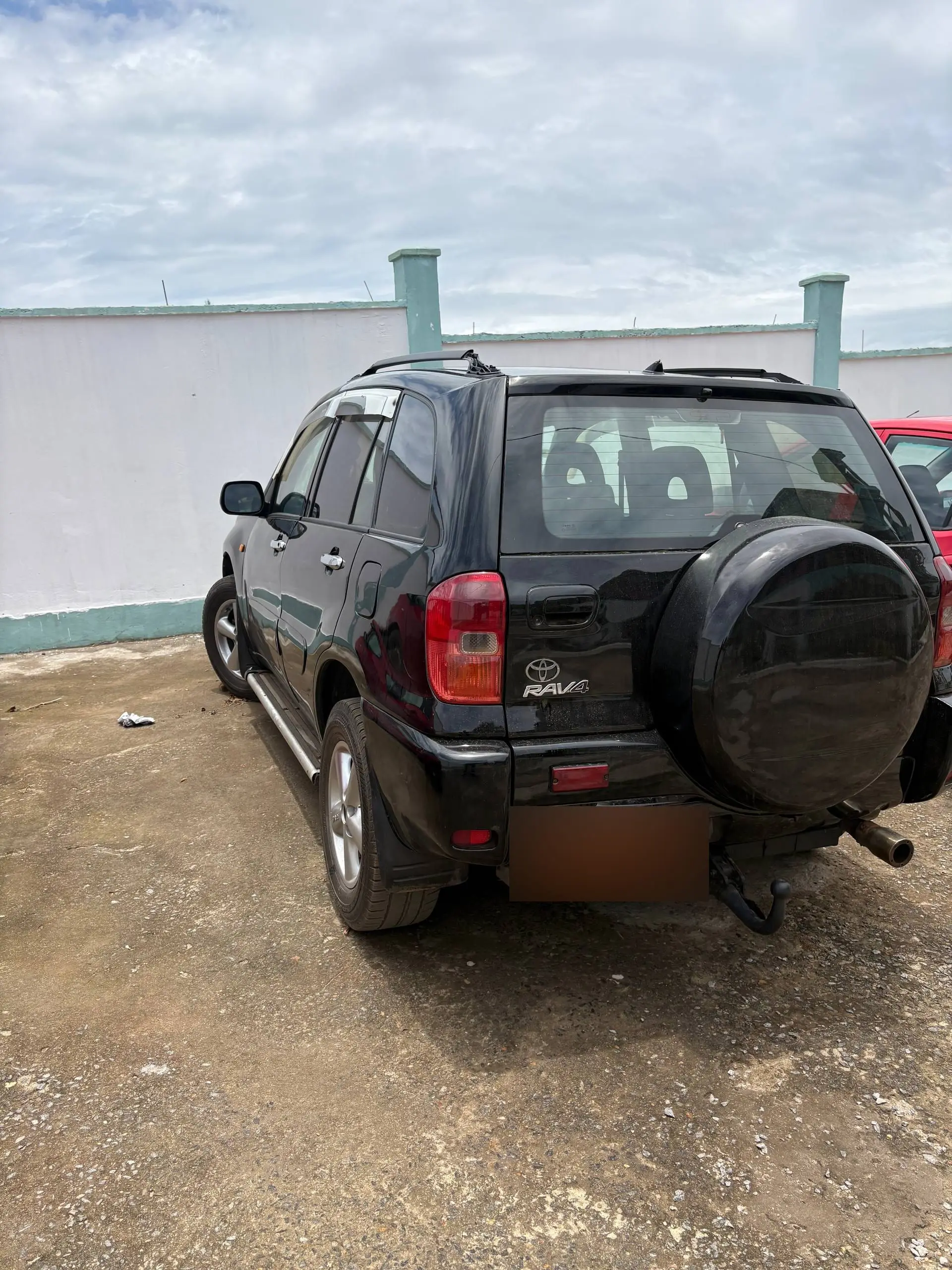 Un Toyota RAV4 noir vu de l'arrière, roue de secours sur le hayon