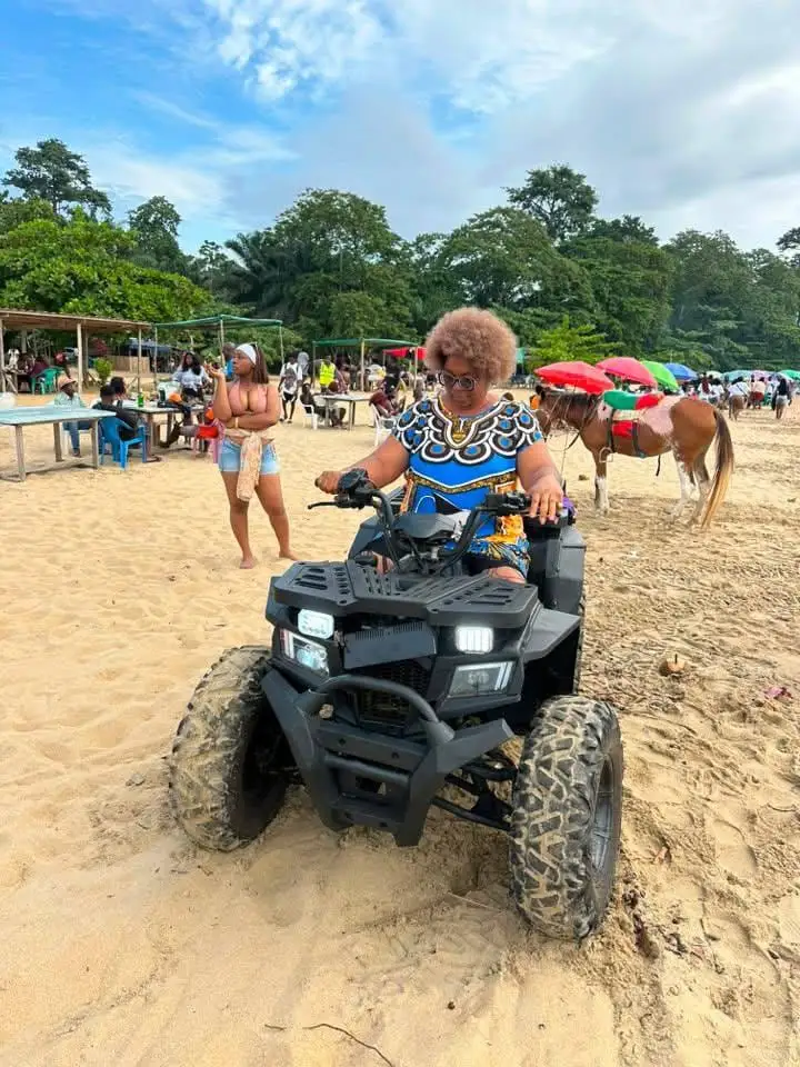Une pilote sur un quad noir, sur la plage animée