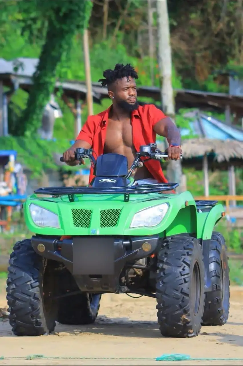 Un pilote sur un quad vert, entre les paillotes